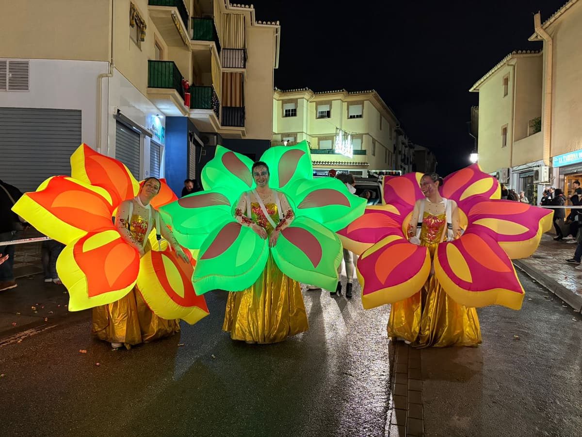 Tres artistas dentro de trajes hinchables de flores gigantes de colores en la calle