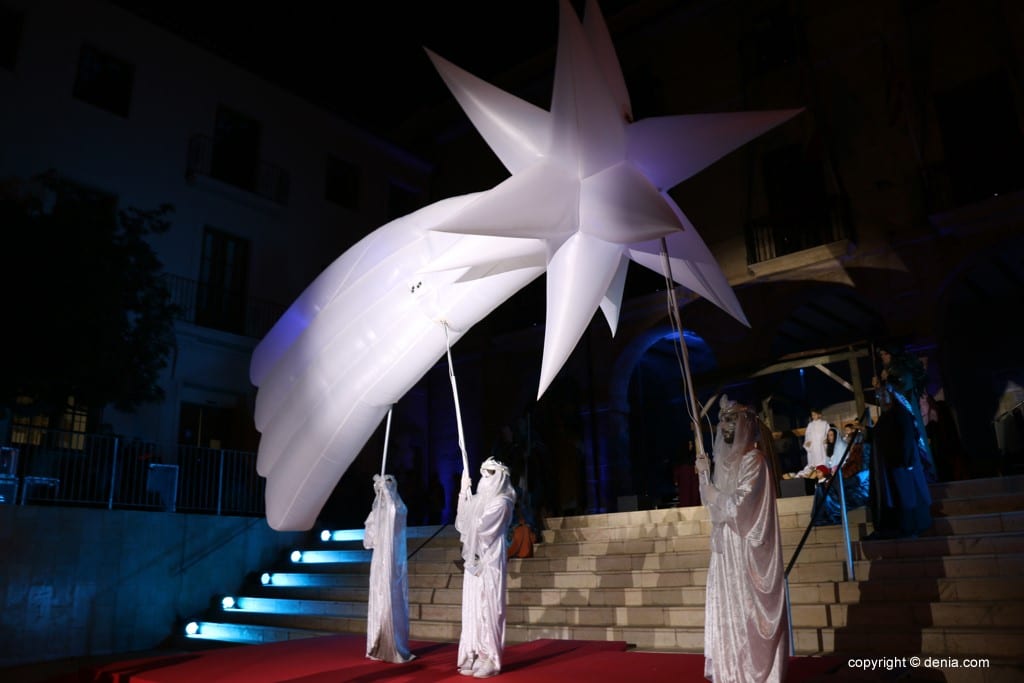 Estrella de Oriente hinchable gigante con cola de cometa sostenida por figurantes con vestuario blanco en cabalgata de Reyes